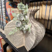 Picture of book cut into shape of a vase with some paper scrapbook flowrs.