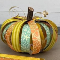 a pumpkin craft made with strips of scrapbook paper