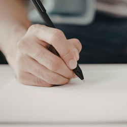 hand holding a pen and writing on paper