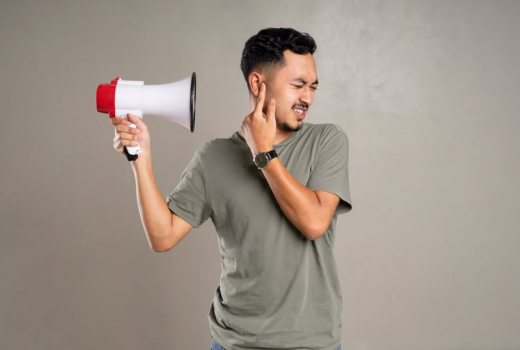 photo of a man covering his ear against a megaphone